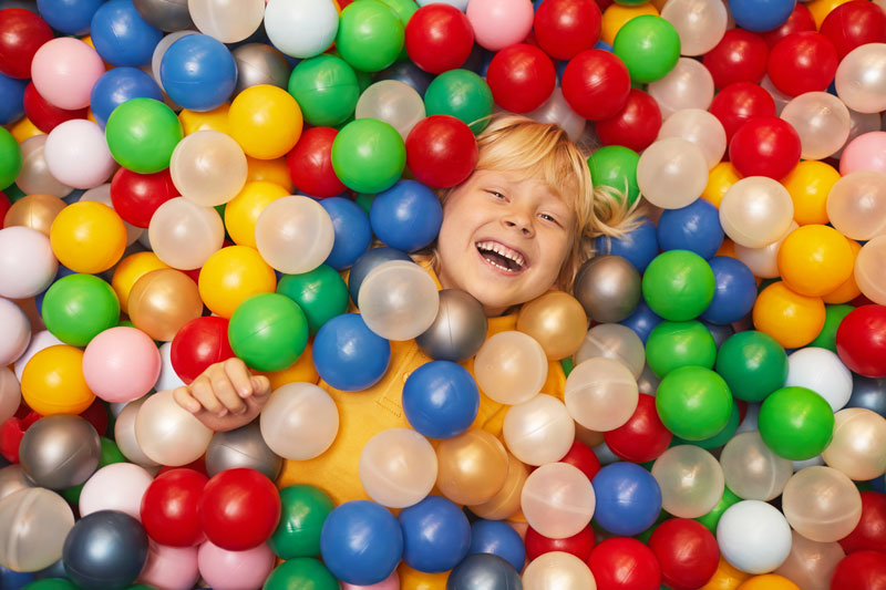 High angle view of happy little boy playing with colored balls